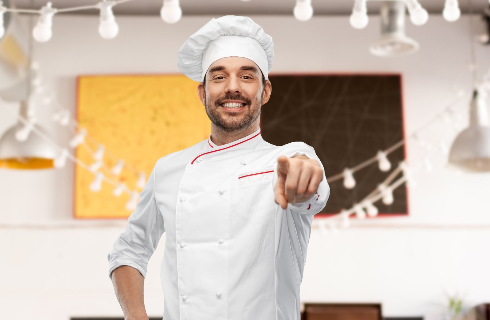 cooking, culinary and people concept - happy smiling male chef in toque pointing finger to camera over restaurant background